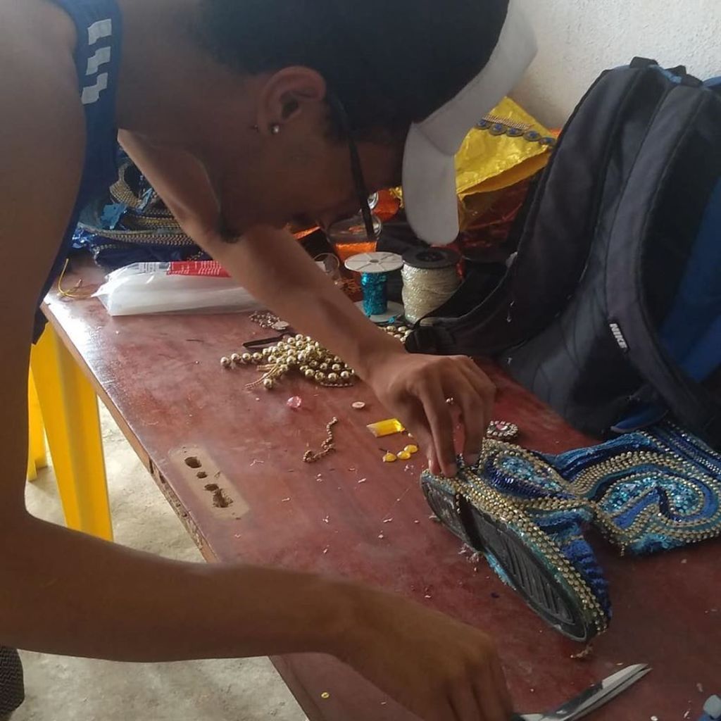 Membro da escola confecciona peça de fantasia que será usada em desfile de Carnaval