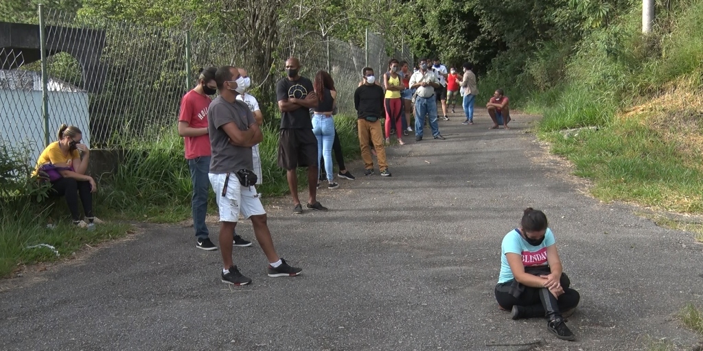 Pessoas aguardam sentadas no chão para realizar o teste de Covid no centro de triagem da Via Expressa