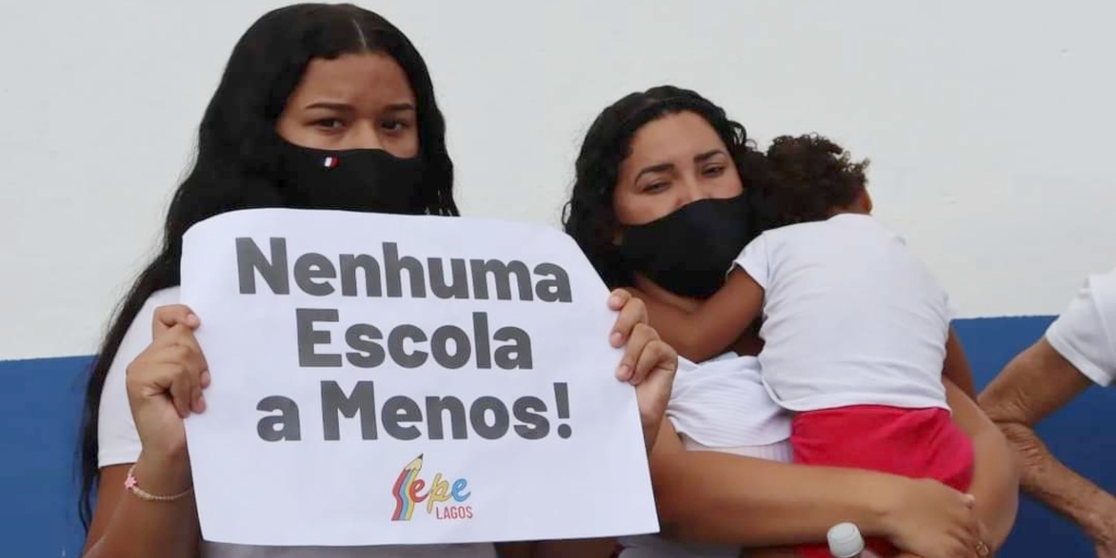 Estudante com cartaz se posicionando contra o fechamento de escolas