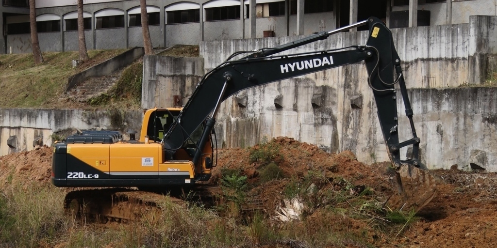 Retroescavadeira trabalha na retirada de terra  