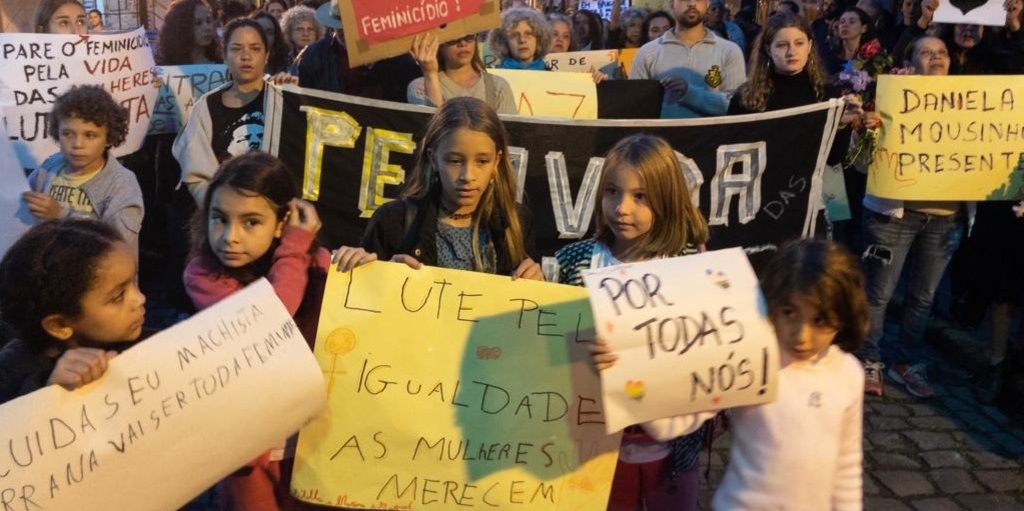 Crianças seguram cartazes durante ato na rua Rodrigues Alves, no Centro de São Pedro da Serra