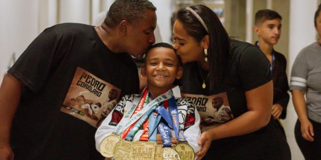 Pedro com suas inúmeras medalhas enquanto recebe o carinho dos pais