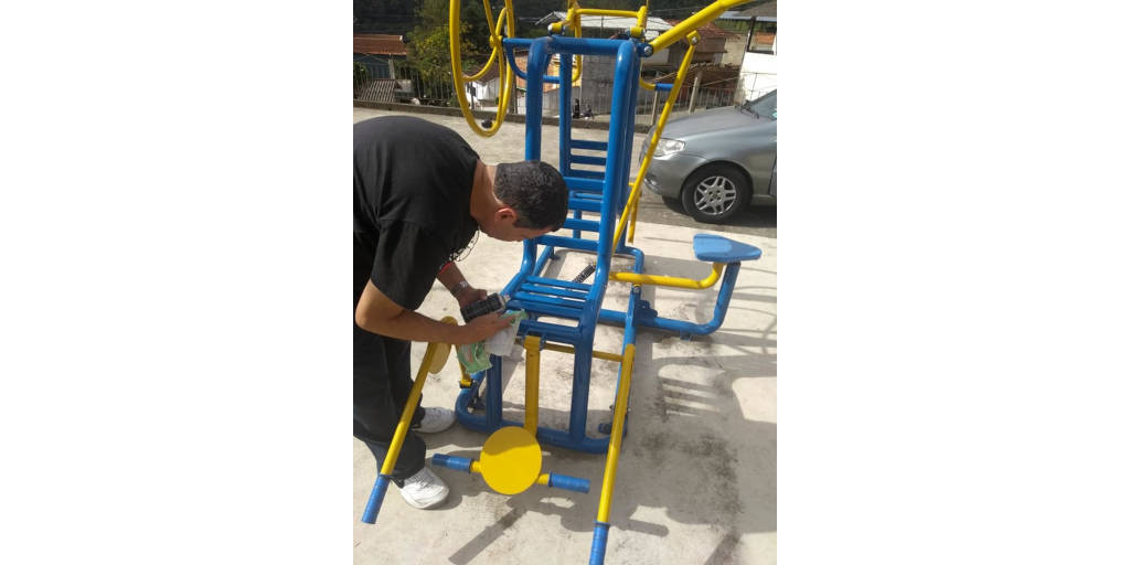 Voluntário pinta equipamento de academia ao ar livre do loteamento